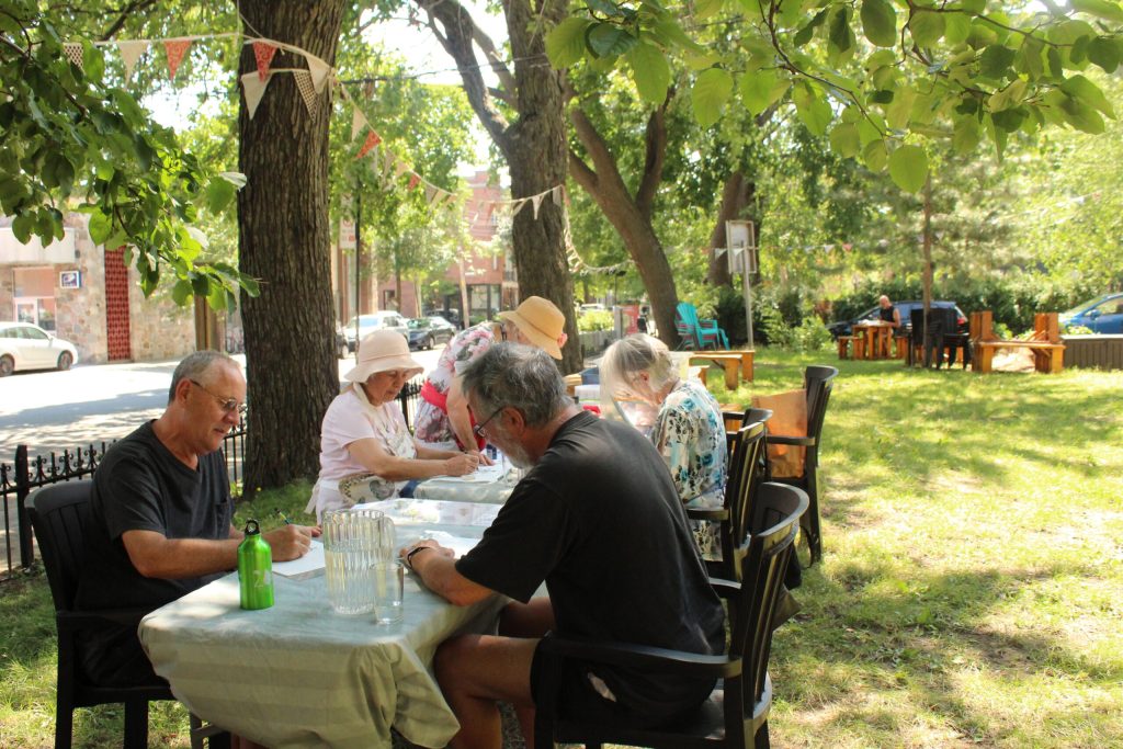 Personnes assises dehors à une table en faisant un projet artistique.